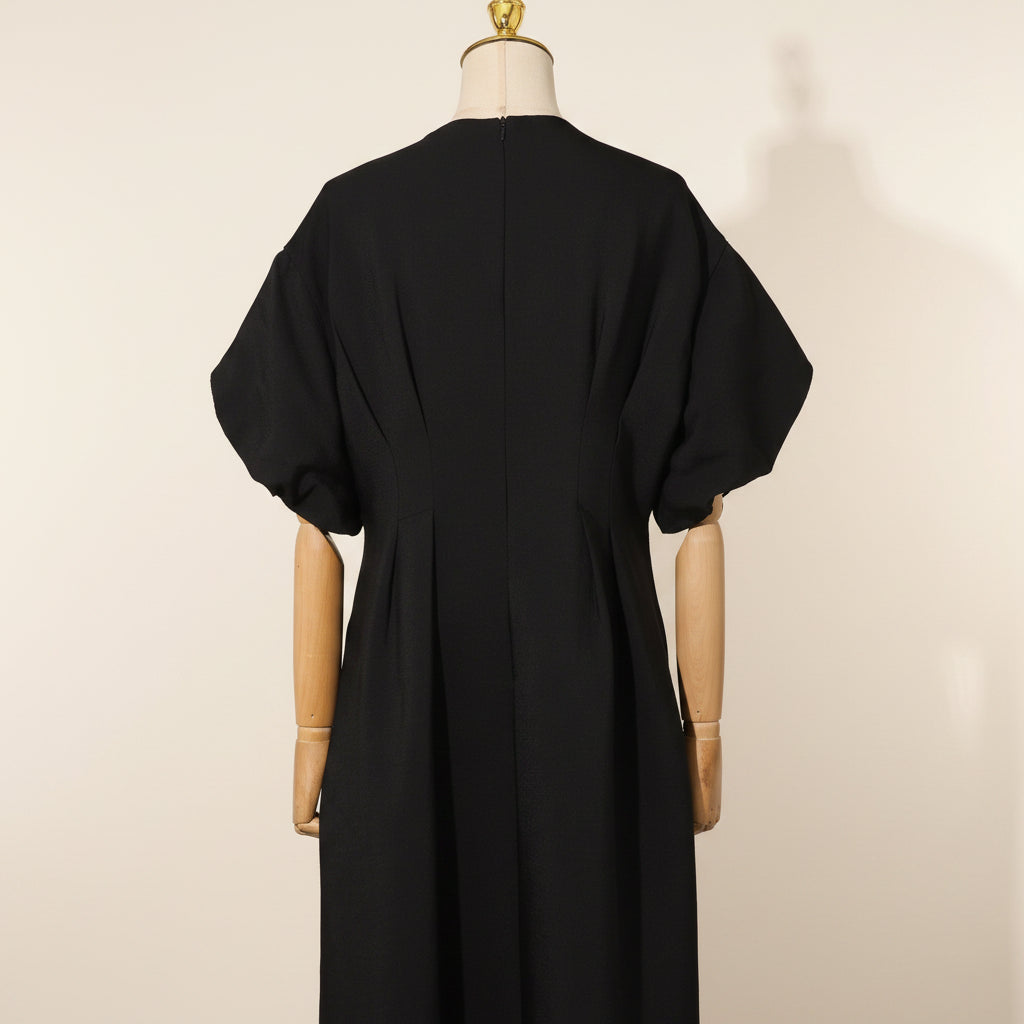 Black dress on a mannequin against a gray curtain background