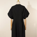 Black dress on a mannequin against a gray curtain background