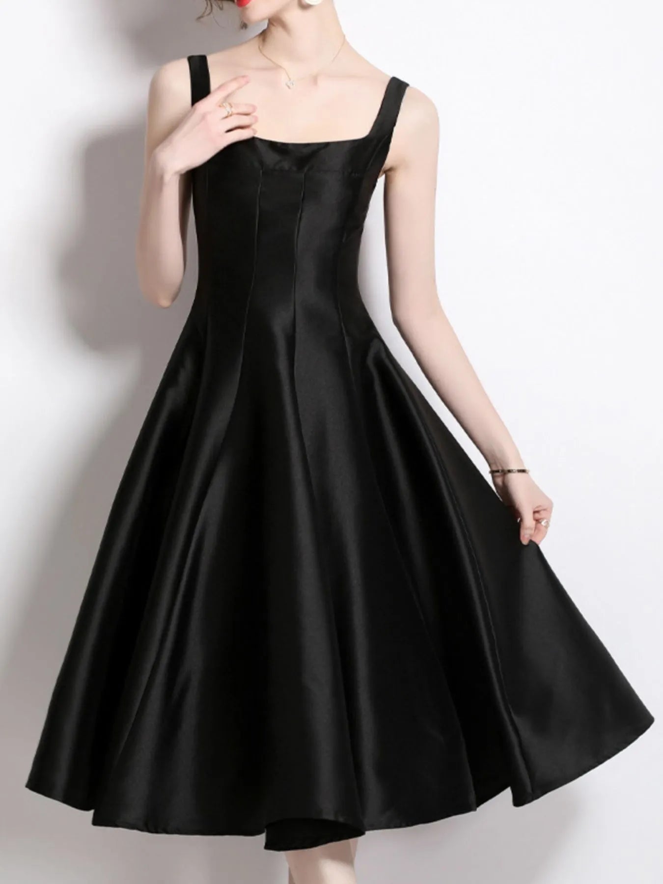 Black dress worn by a model on a plain background