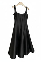 Black sleeveless dress on a hanger against a white background