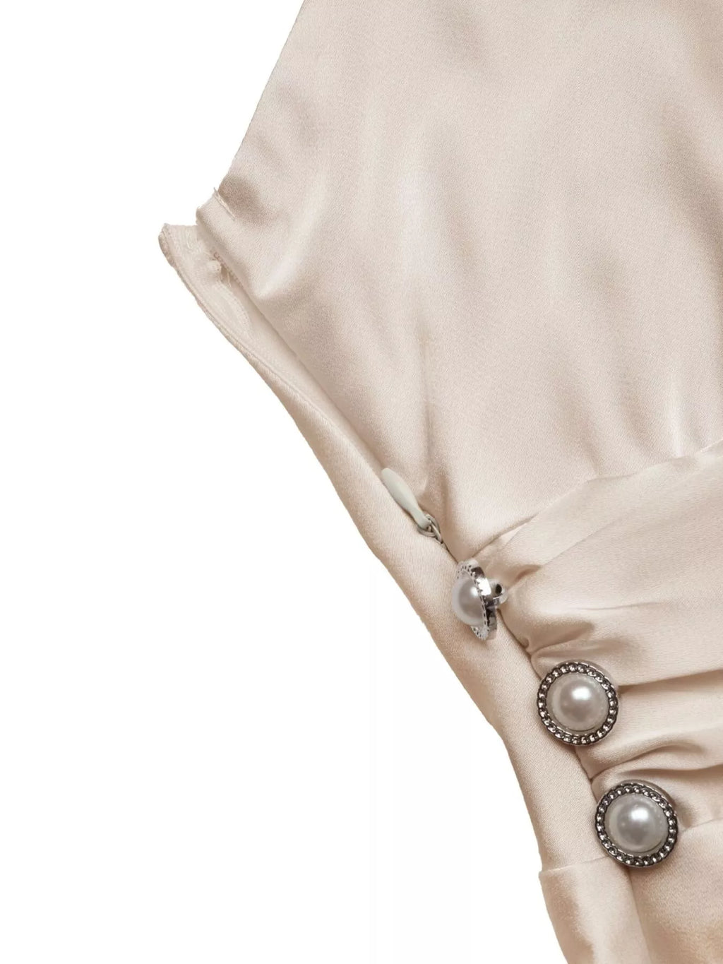 Close-up of a beige garment with pearl buttons on a white background