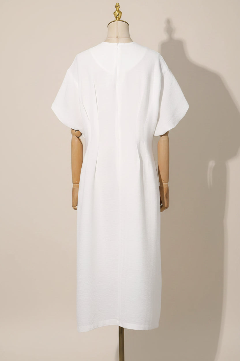 White dress on a mannequin against a gray curtain background