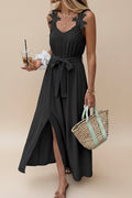 Woman wearing a black dress with lace details, holding a straw bag, standing on a street.