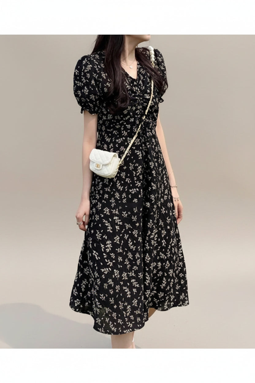 Woman wearing a black floral dress standing on grass
