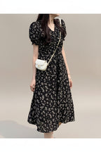 Woman wearing a black floral dress standing on grass