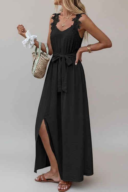 Woman wearing a black sleeveless dress with lace details, standing against a neutral background.