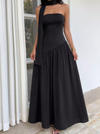 Woman wearing a black strapless dress with a flowing skirt in an outdoor setting.
