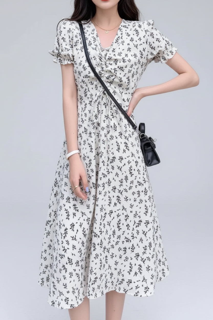 Woman wearing a white floral dress standing outdoors on a tiled floor.